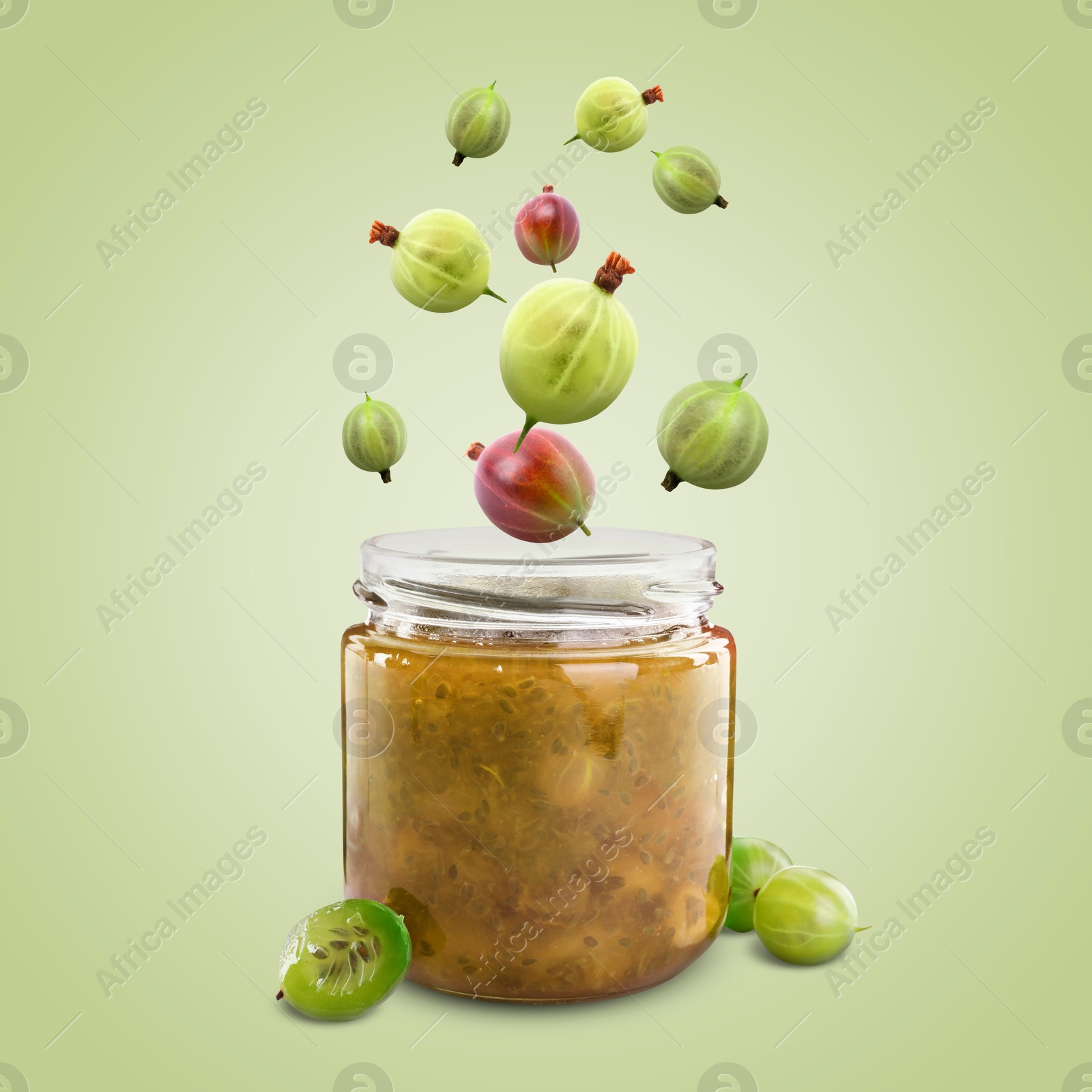 Image of Gooseberries falling into jar with berry jam on light green background