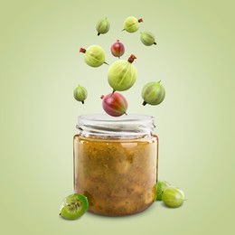 Image of Gooseberries falling into jar with berry jam on light green background