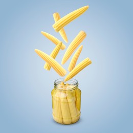 Image of Baby corn cobs falling into jar on light blue background