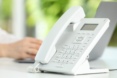 White telephone on table against blurred background, selective focus