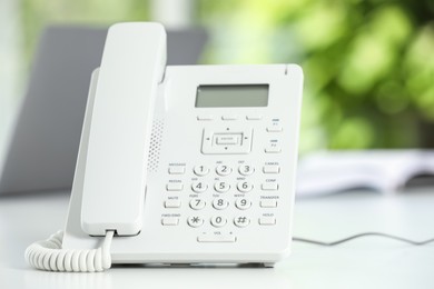 White telephone on table against blurred background, closeup