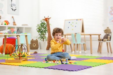 Cute little boy playing with math game Fishing for Numbers on puzzle mat in kindergarten