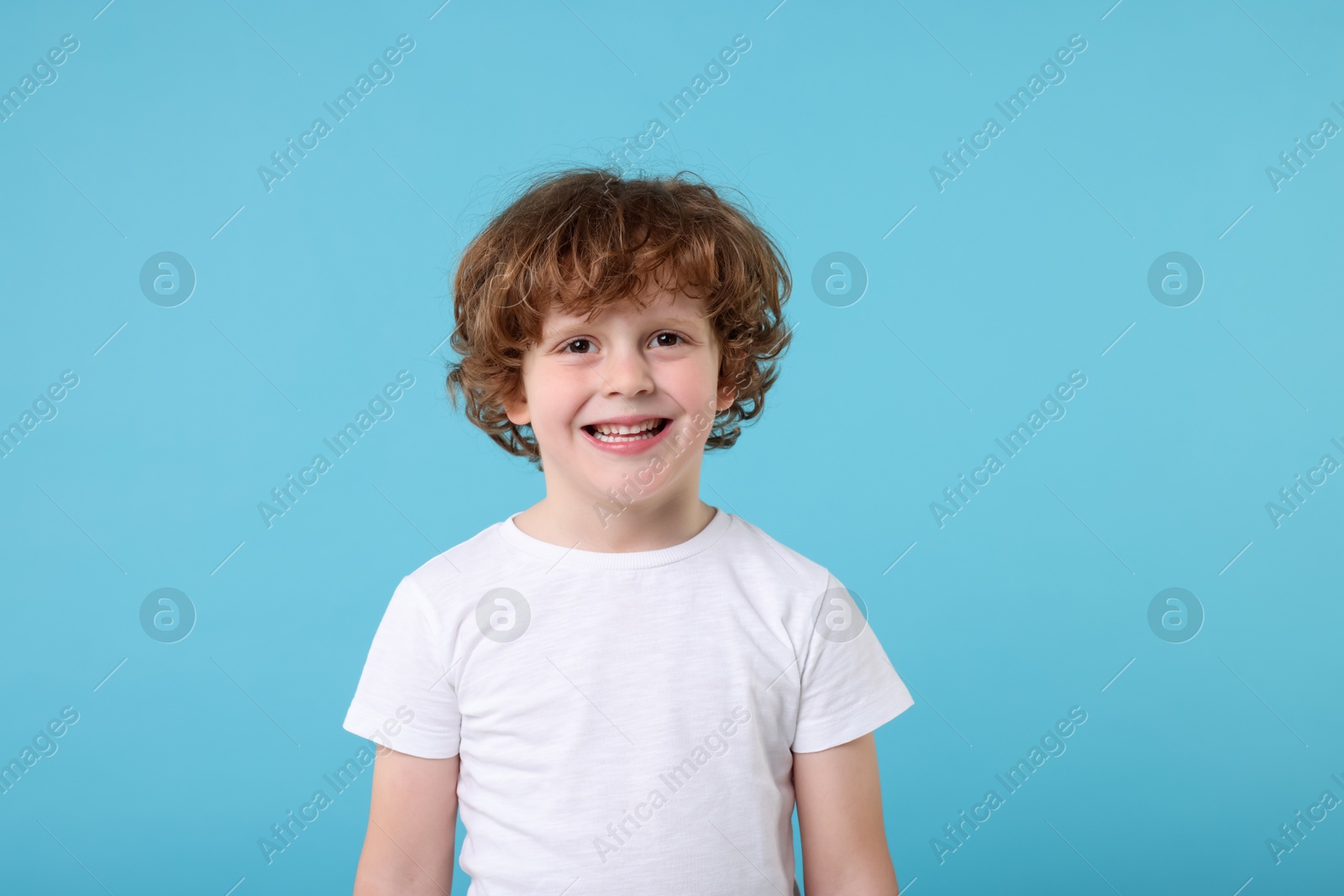 Photo of Portrait of cute little boy on light blue background