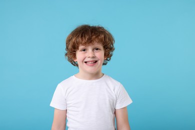 Portrait of cute little boy on light blue background