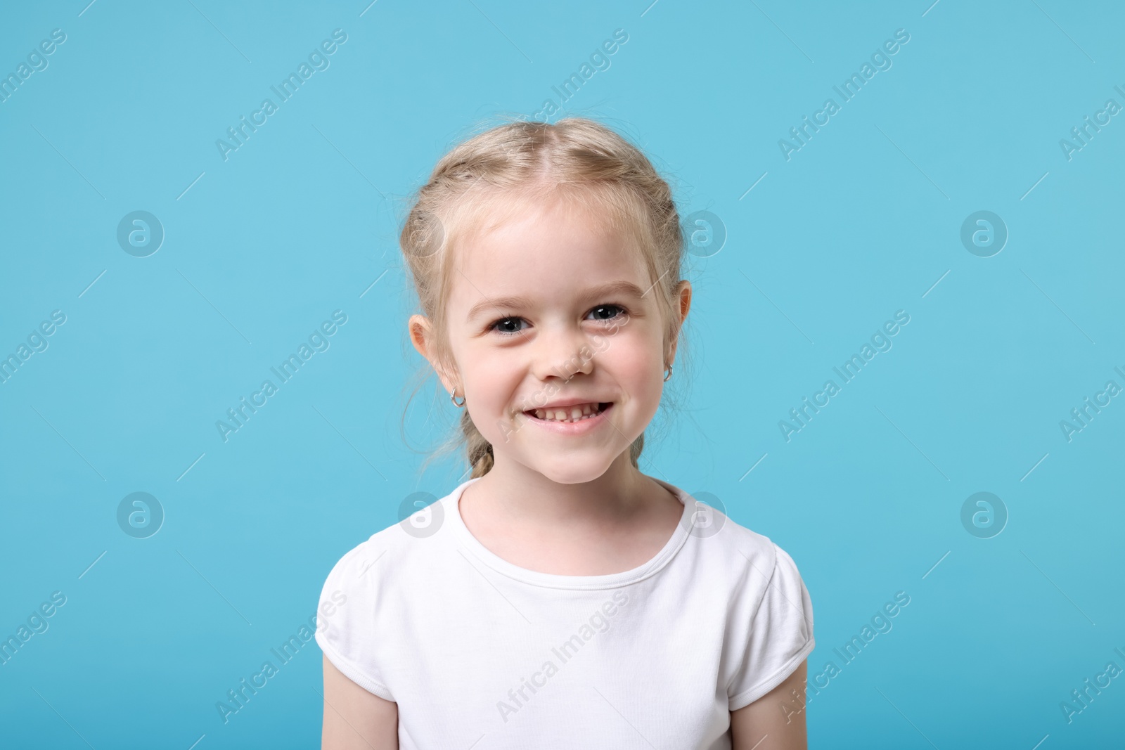 Photo of Portrait of cute little girl on light blue background