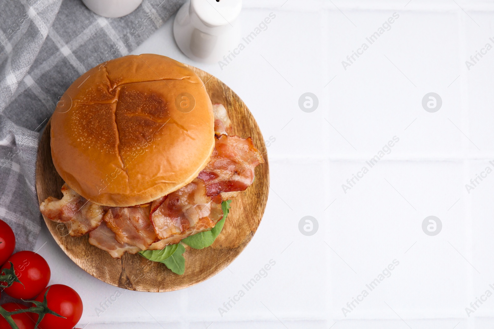 Photo of Delicious burger with bacon and greens on white table, flat lay. Space for text