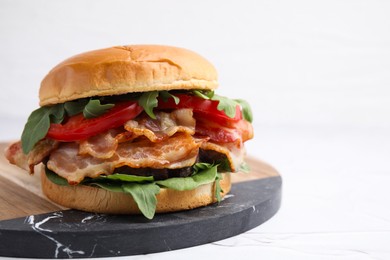 Delicious burger with bacon, tomato and greens on light background, closeup. Space for text