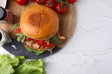 Delicious burger with bacon, tomatoes and lettuce on light textured table, flat lay. Space for text