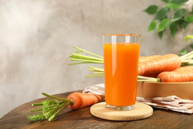 Healthy carrot juice in glass and fresh vegetables on wooden table. Space for text