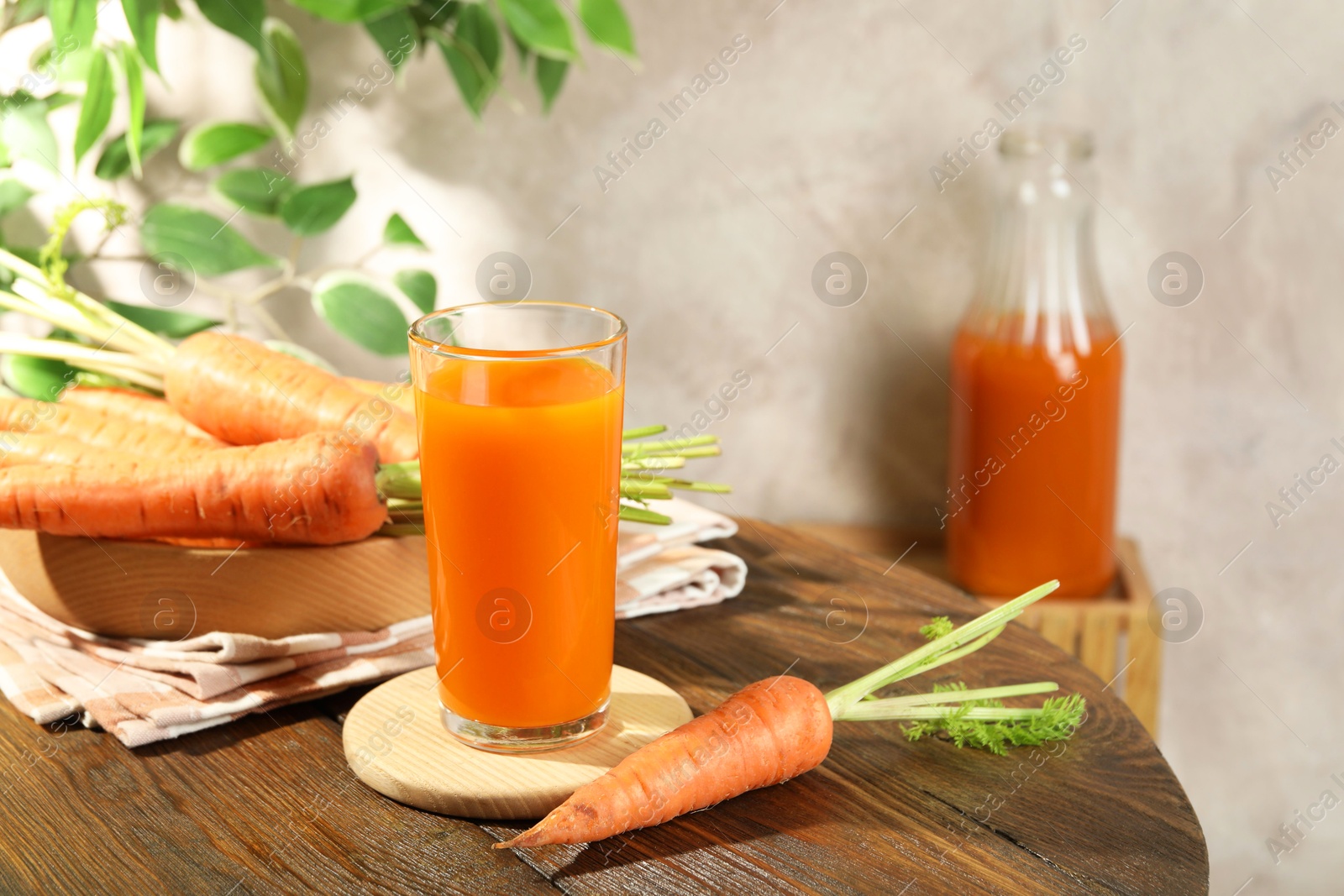 Photo of Healthy carrot juice in glass and fresh vegetables on wooden table