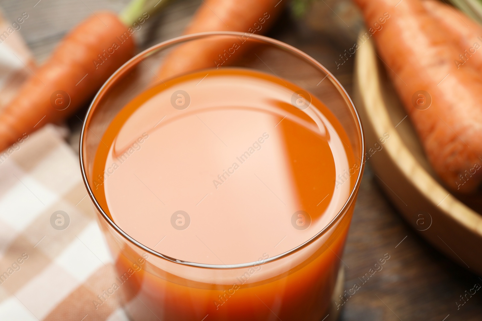 Photo of Healthy carrot juice in glass and fresh vegetables on table, closeup