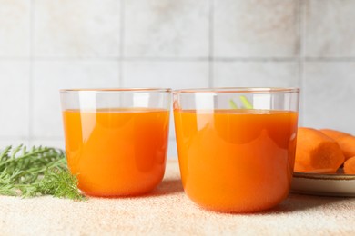 Photo of Healthy carrot juice in glasses and fresh vegetable on color textured table