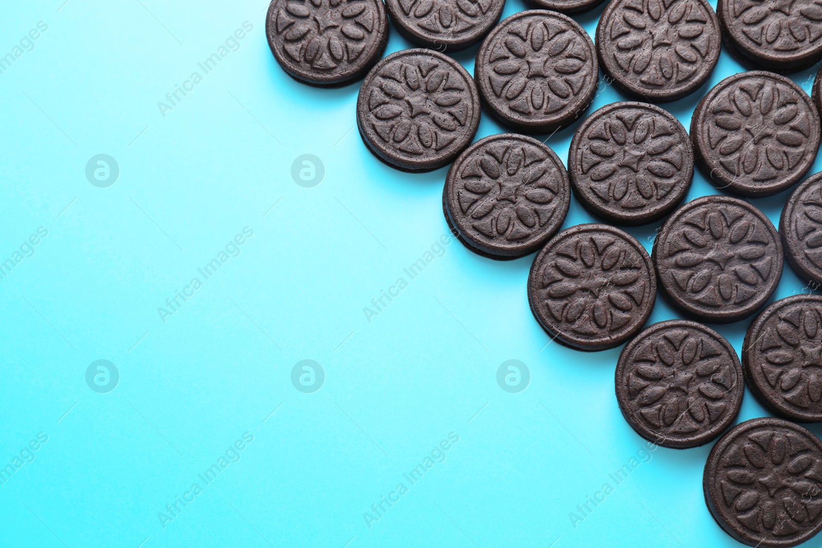 Photo of Tasty sandwich cookies on light blue background, top view. Space for text