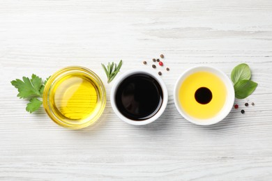 Photo of Balsamic vinegar, oil and other products on white wooden table, flat lay