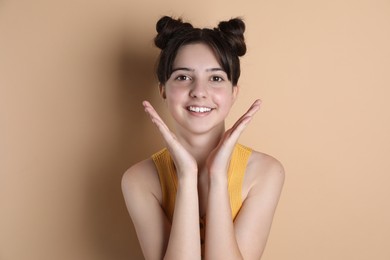 Portrait of smiling teenage girl on beige background