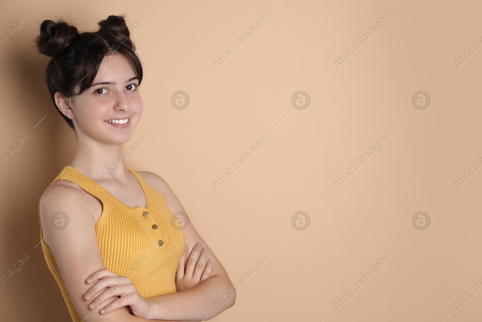 Photo of Portrait of smiling teenage girl on beige background. Space for text