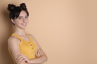 Portrait of smiling teenage girl on beige background. Space for text