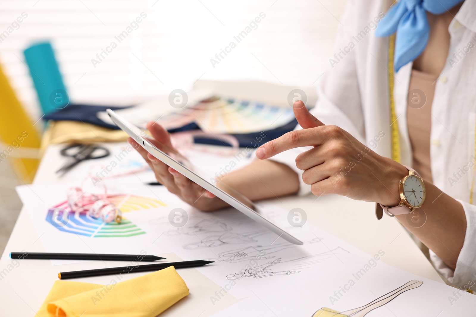 Photo of Fashion designer with tablet working at table in workshop, closeup