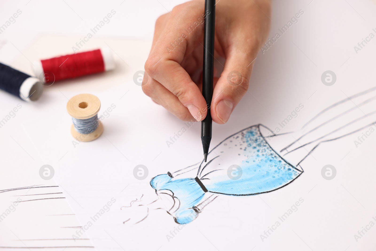 Photo of Fashion designer drawing sketch of dress at table, closeup