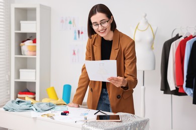 Photo of Fashion designer with sketch at table in workshop