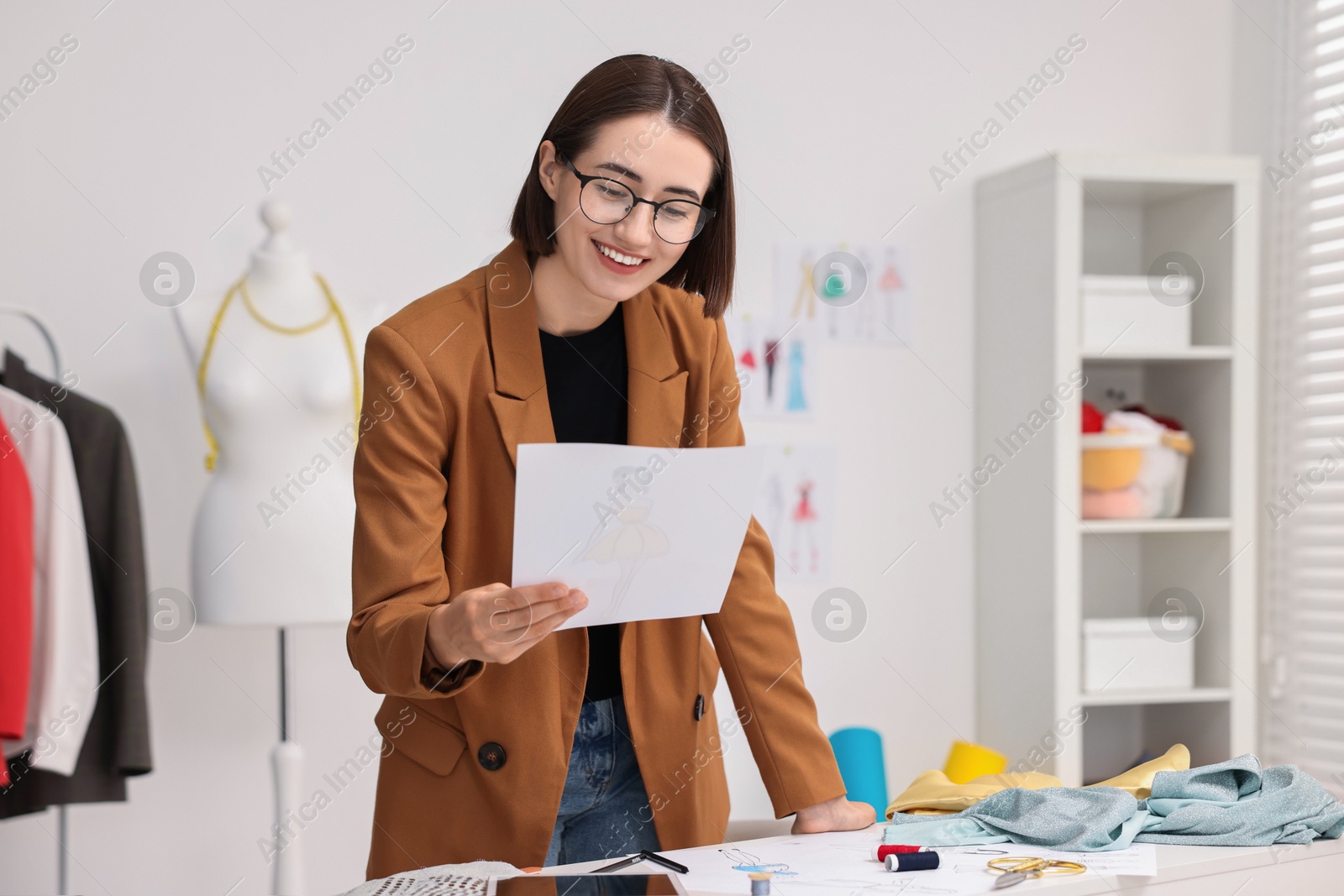 Photo of Fashion designer with sketch at table in workshop