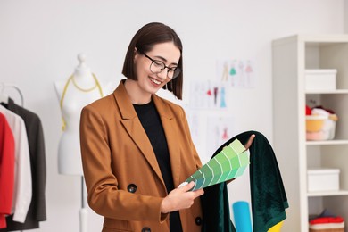 Photo of Fashion designer with color palettes and fabric in workshop