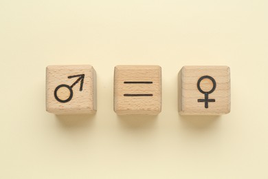 Photo of Gender equality concept. Wooden cubes with male and female symbols on beige background, flat lay