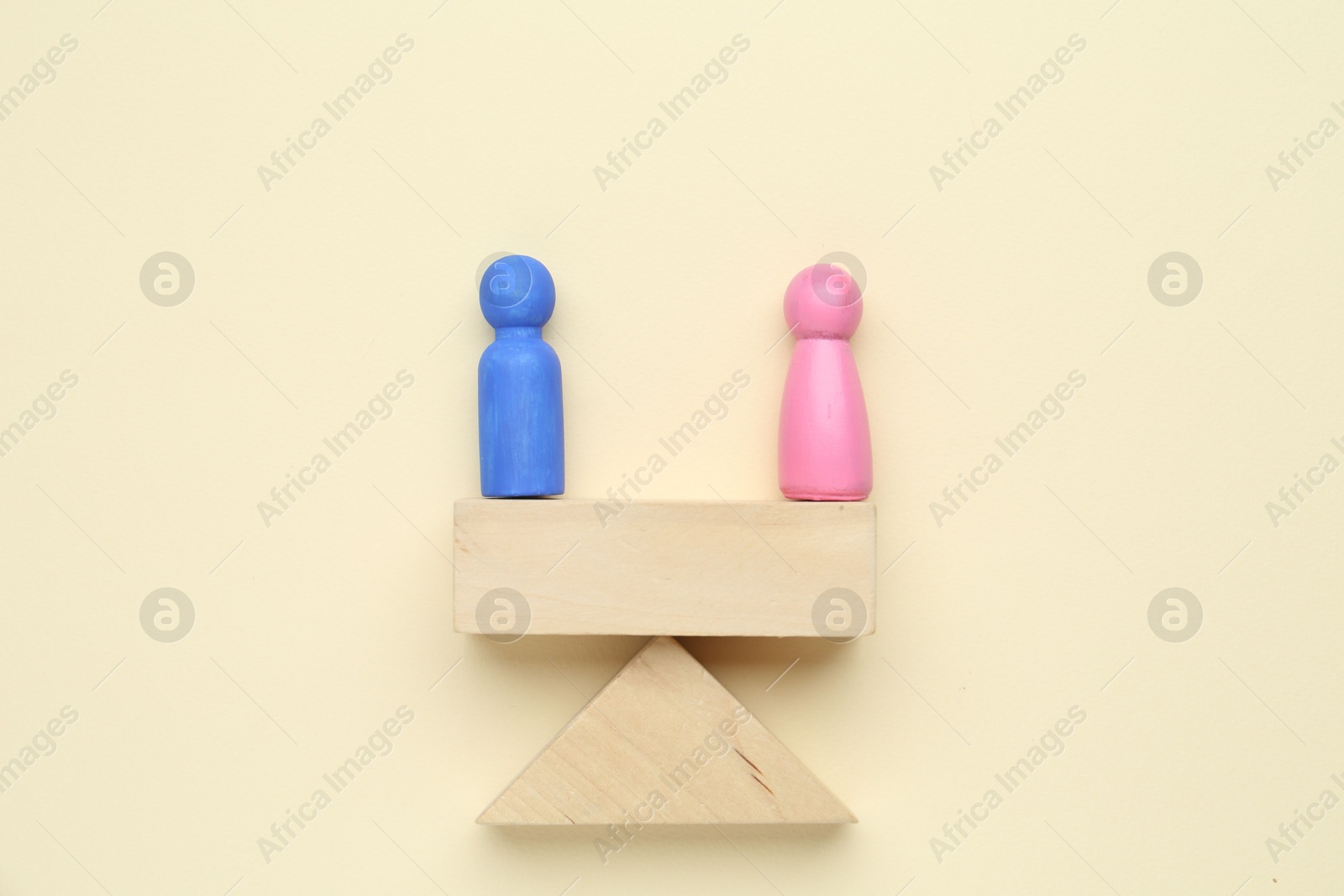 Photo of Gender equality concept. Male and female figures on scales against beige background, flat lay