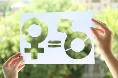 Photo of Gender equality concept. Woman holding paper with female and male symbols outdoors, closeup