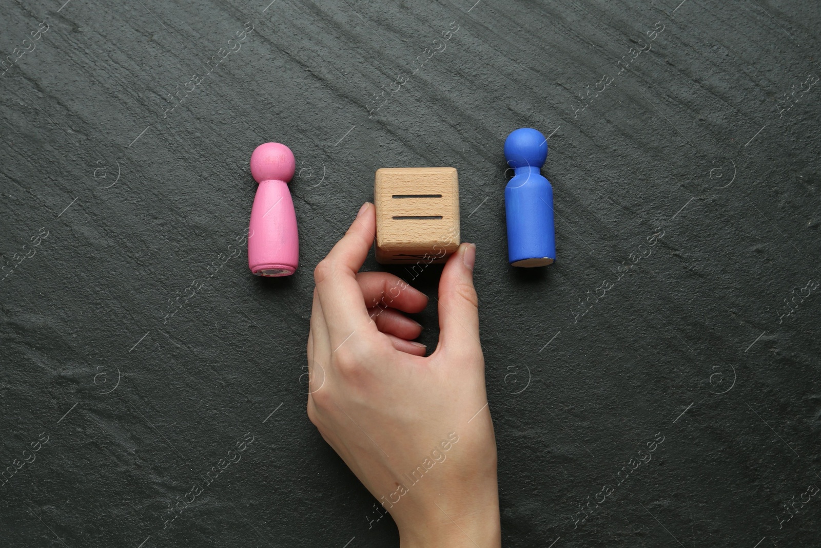 Photo of Gender equality concept. Woman holding wooden cube with equals sign between female and male figures at grey textured background, top view