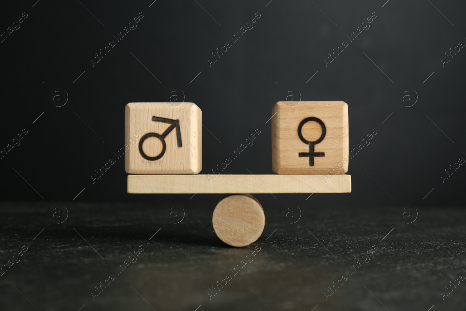 Photo of Wooden balance scales with cubes showing concept of equality between men and women against grey background