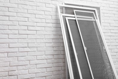 Set of window screens near white brick wall. Space for text