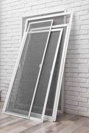 Photo of Set of window screens near white brick wall indoors