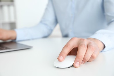 Photo of Man working with wireless mouse at white table indoors, closeup