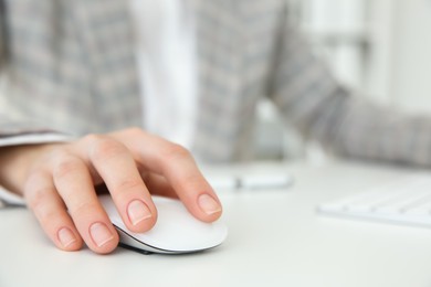 Photo of Woman working with wireless mouse at white table indoors, closeup