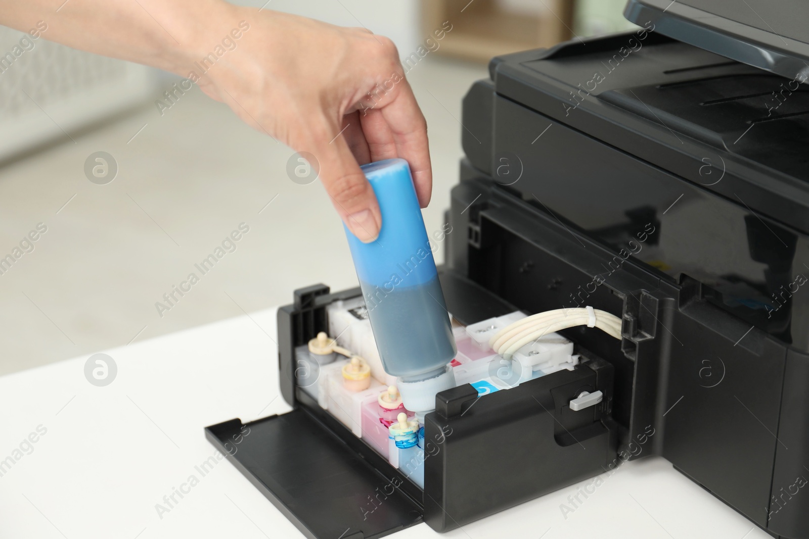 Photo of Woman refilling ink in modern printer at workplace indoors, closeup