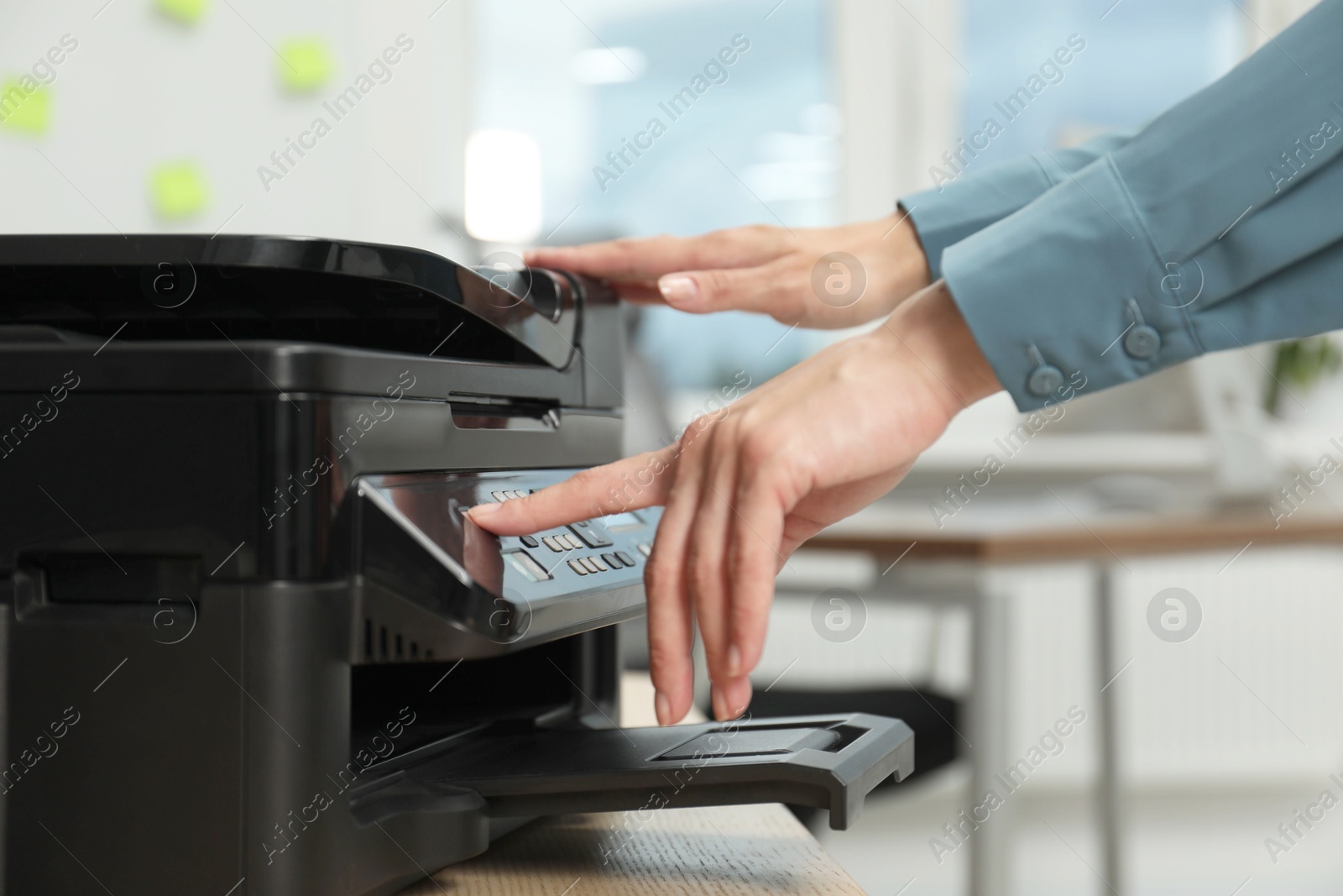 Photo of Woman using modern printer at workplace indoors, closeup