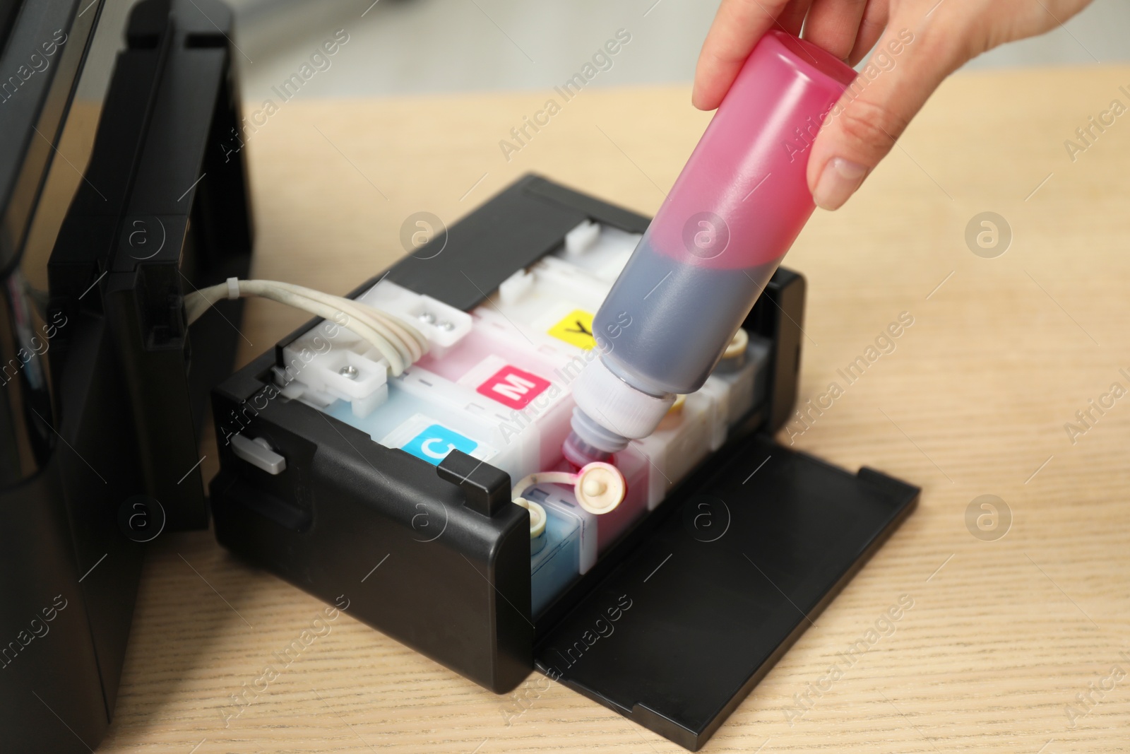 Photo of Woman refilling ink in modern printer at workplace indoors, closeup