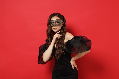 Photo of Beautiful woman wearing carnival mask on red background