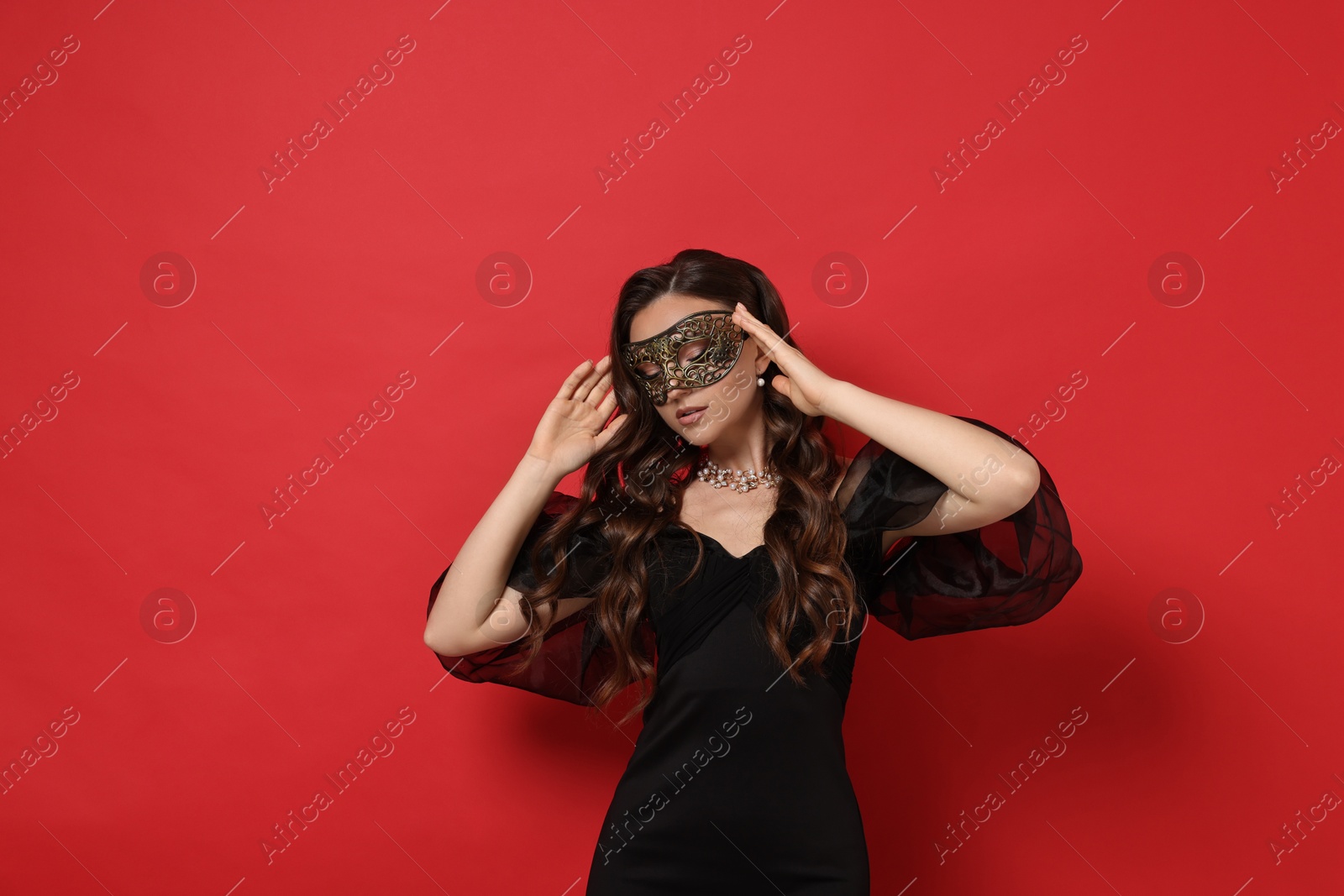 Photo of Beautiful woman wearing carnival mask on red background. Space for text