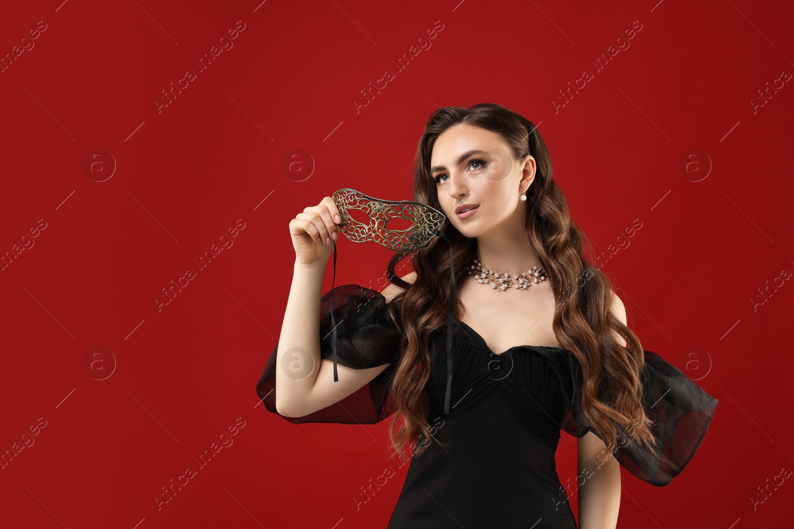 Photo of Beautiful woman with carnival mask on red background. Space for text