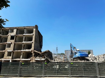 Photo of Demolition of building with excavator under blue sky