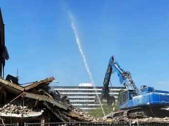 Photo of Demolition of building with excavator under blue sky