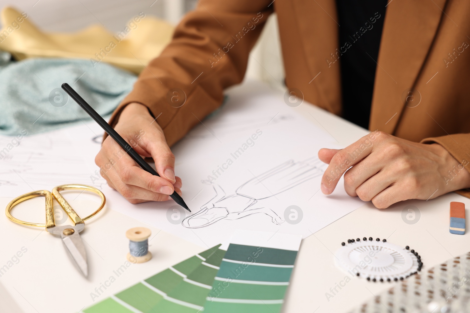 Photo of Fashion designer drawing sketch of dress at table, closeup