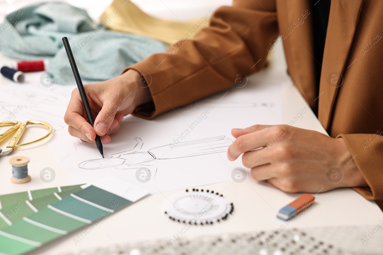 Photo of Fashion designer drawing sketch of dress at table, closeup