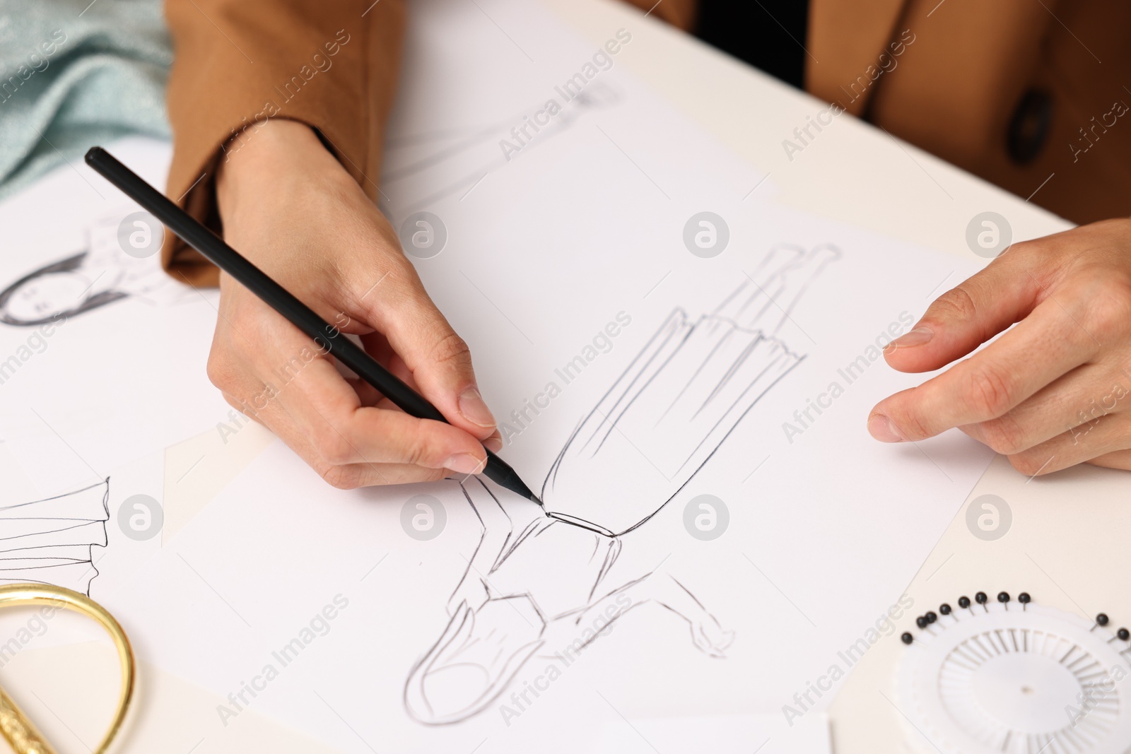 Photo of Fashion designer drawing sketch of dress at table, closeup