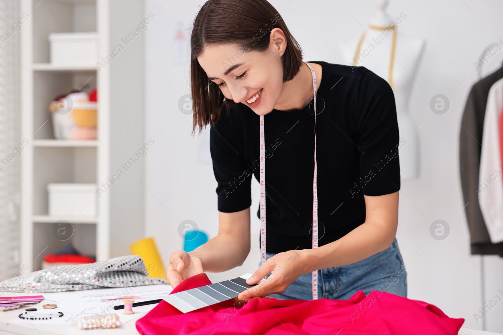 Photo of Fashion designer with color palette and pink at table in workshop