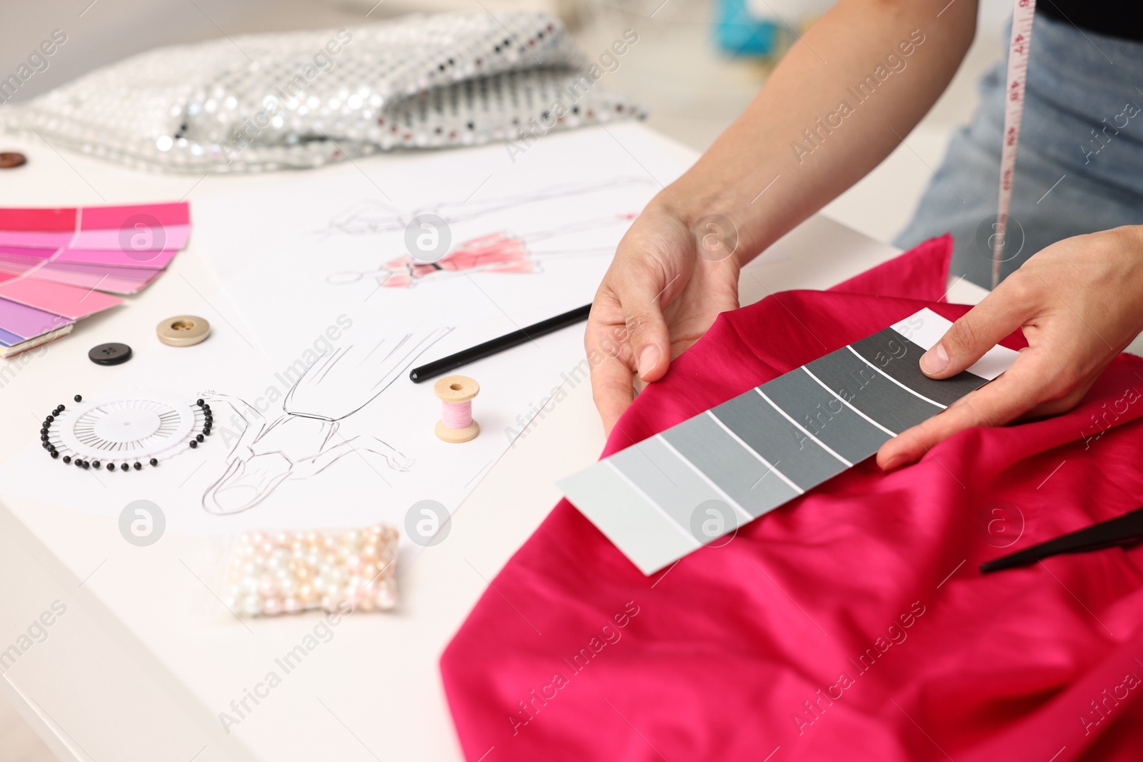 Photo of Fashion designer with color palette and pink at table in workshop, closeup