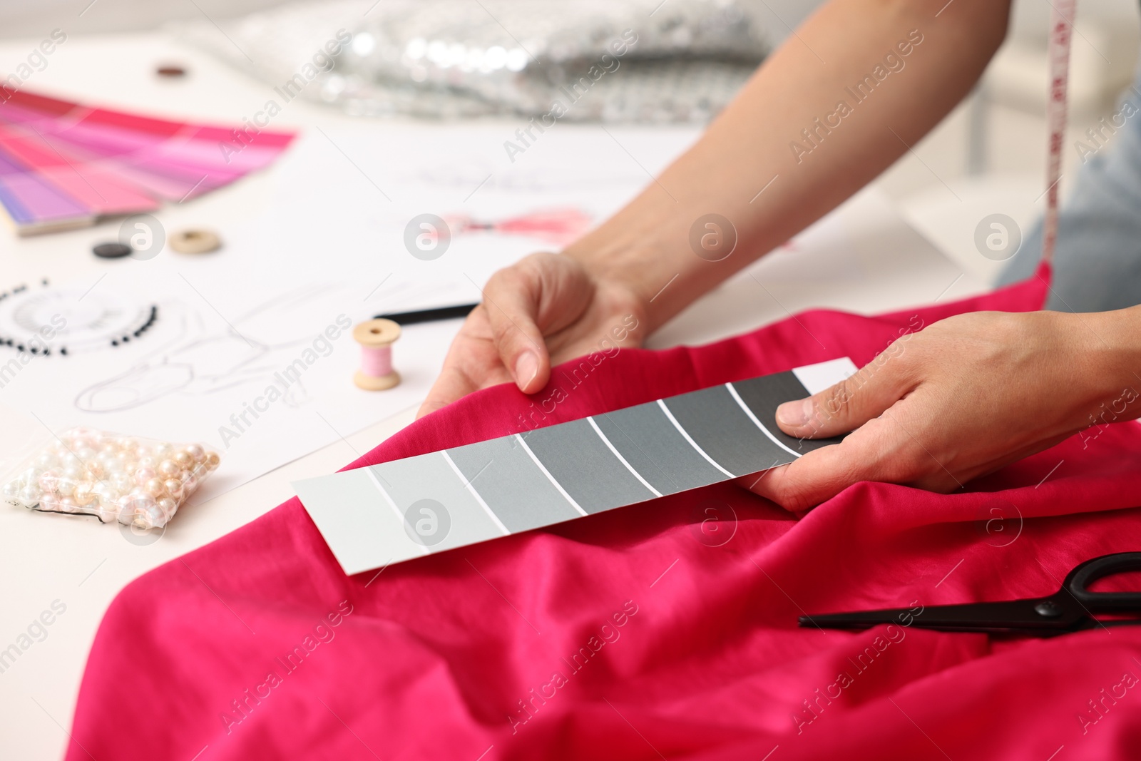 Photo of Fashion designer with color palette and pink at table in workshop, closeup