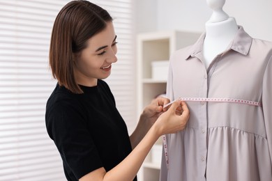 Fashion designer with measuring tape working in workshop